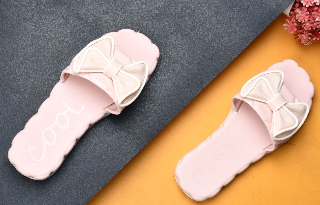 Elegant pink slippers with bows on textured background, perfect for fashion and lifestyle themes.