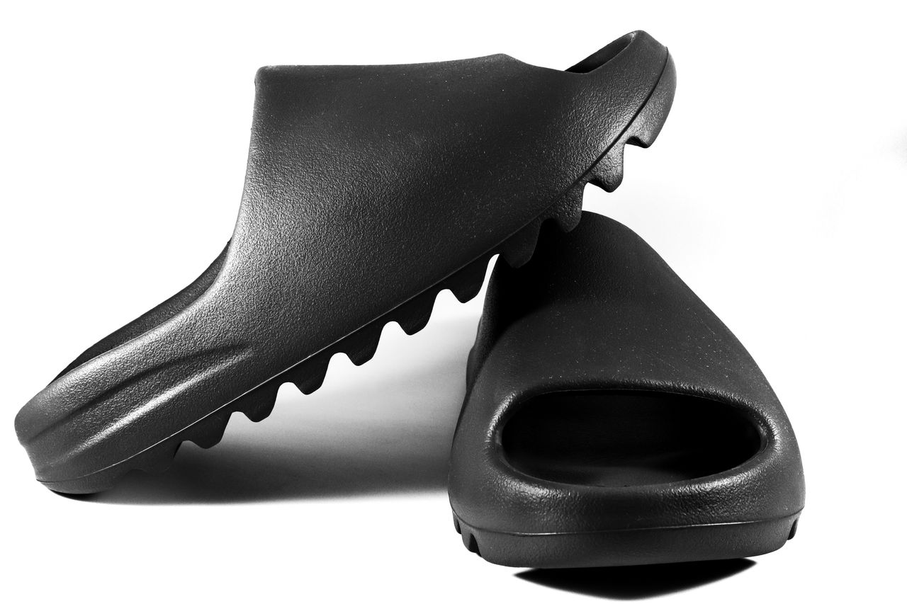 Close-up of black slide sandals on a white surface, showcasing modern minimalist design.