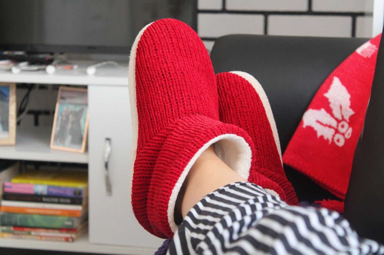 Comfortable relaxation at home with fluffy red slippers and a cozy setting.
