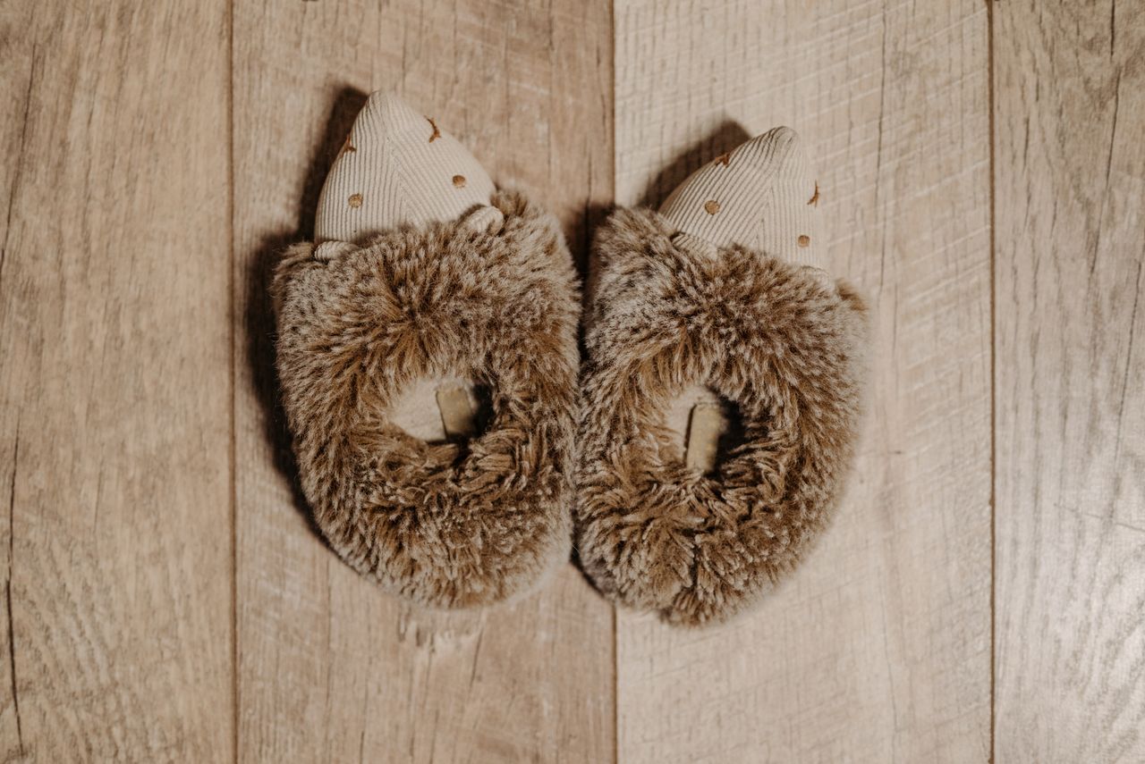 Top view of cute and cozy furry slippers placed on a wooden surface, perfect for warmth and comfort.